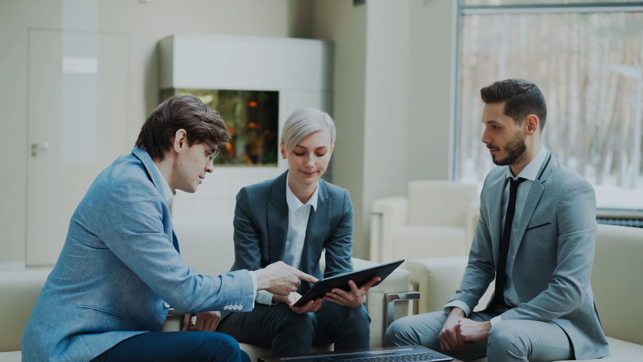 The Art of Drawing Readers In: Your attractive post title goes here Three professionals engaging in a business meeting in a modern office setting.